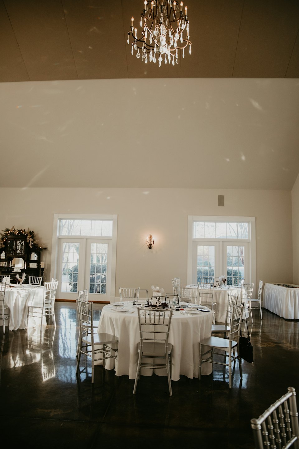 Empty ballroom with round tables and silver chairs for an event.
