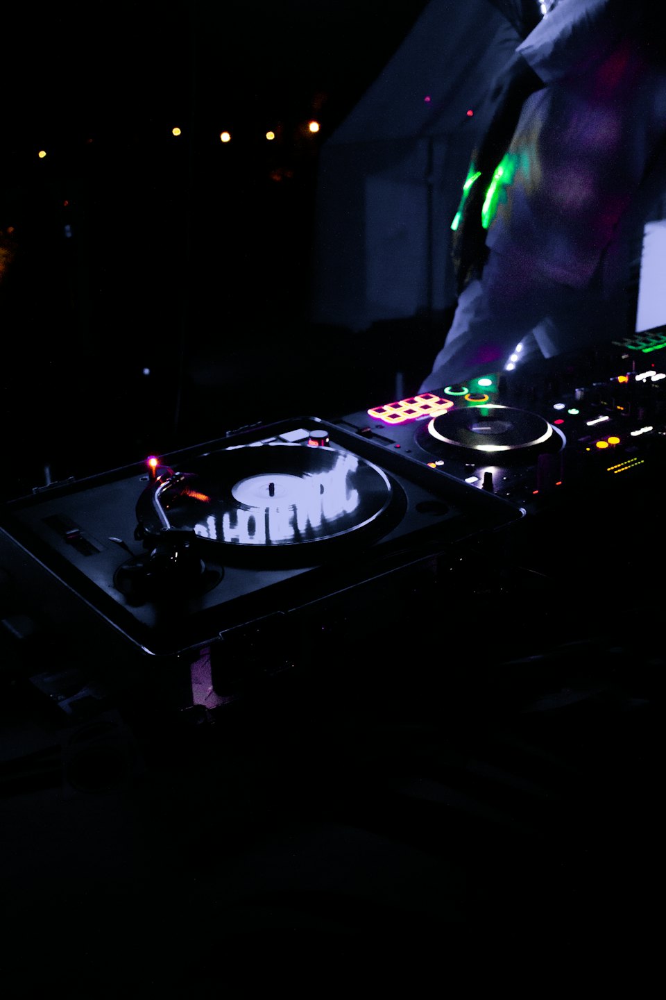 DJ mixing music on turntables with colorful lights.